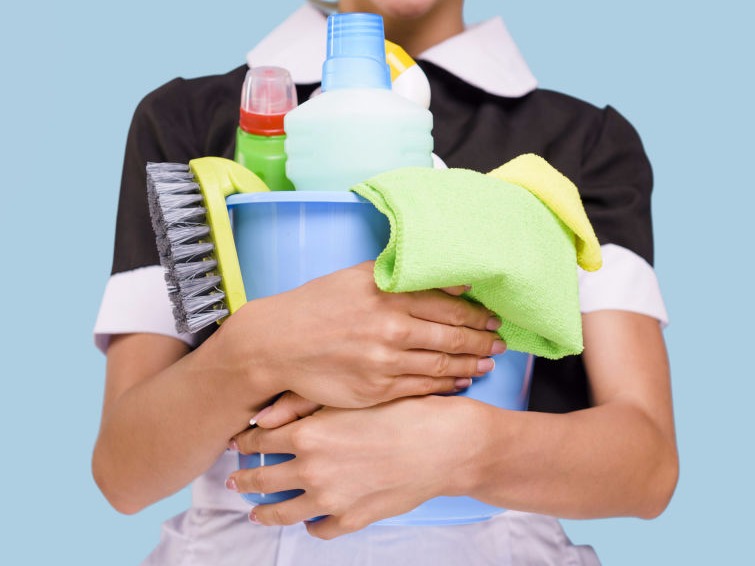 Woman holding a bucket of cleaning tools and solution